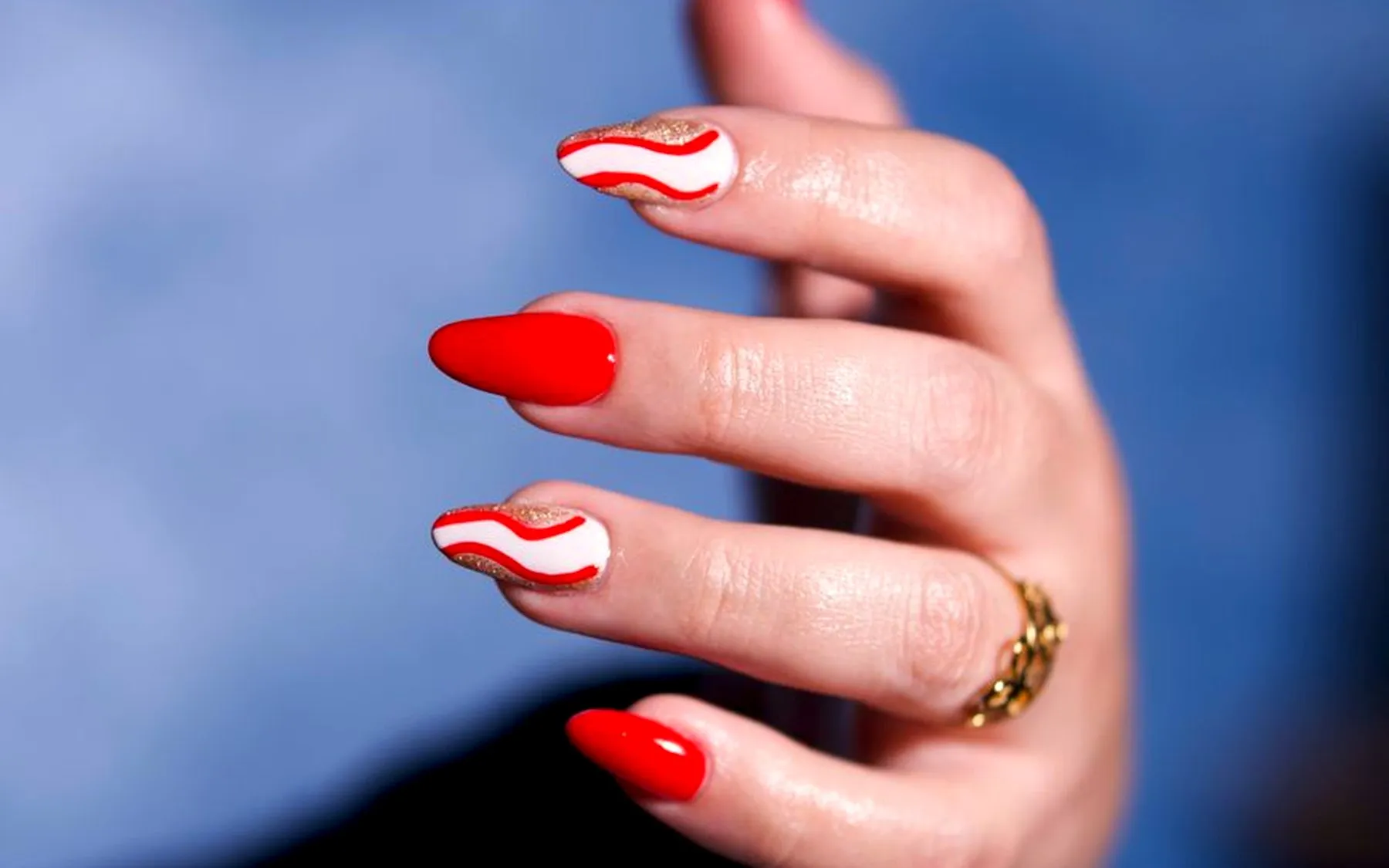 Mão com unhas vermelhas sobre um fundo azul
