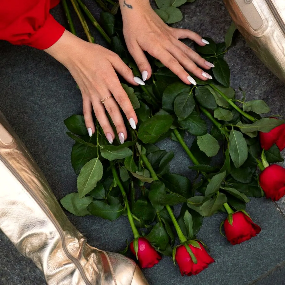 Mão com unhas escuras sobre rosas
